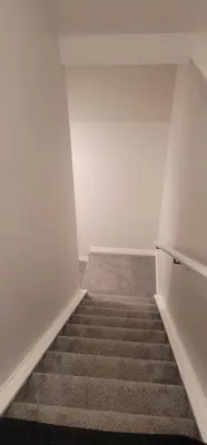 an empty room with a staircase with white walls and carpet at A Cozy home away from home at South East Calgary in Calgary