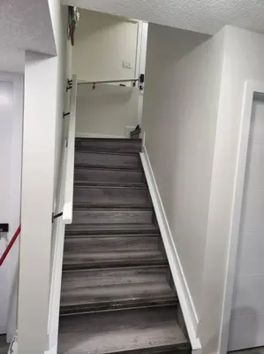 a staircase in a room with white walls and wooden floors at Modern 2 Bedroom Basement Suite Chappelle Edmonton in Edmonton