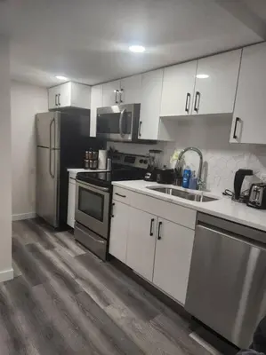 a kitchen with white cabinets and stainless steel appliances at Modern 2 Bedroom Basement Suite Chappelle Edmonton in Edmonton