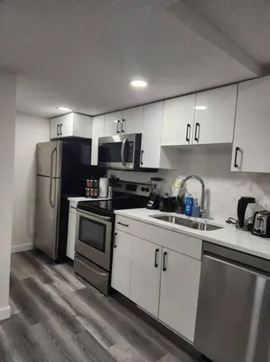 a kitchen with white cabinets and stainless steel appliances at Modern 2 Bedroom Basement Suite Chappelle Edmonton in Edmonton