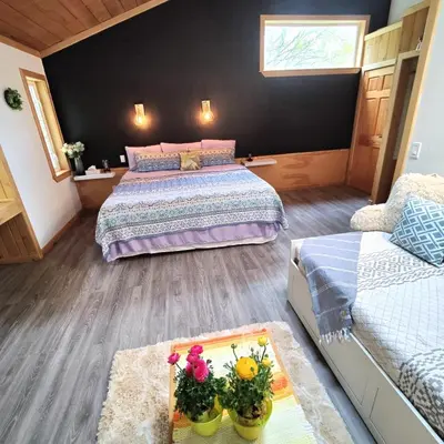 a bedroom with two beds and a table with flowers on it at Hummingbird B&B in Gabriola