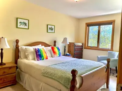 a bedroom with a bed and a chair and a window at C303 Hidden Gem with MTN andCreek View, Quiet and Private in Canmore