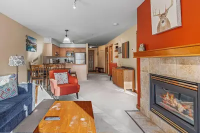 a living room with a fireplace and a kitchen at C303 Hidden Gem with MTN andCreek View, Quiet and Private in Canmore