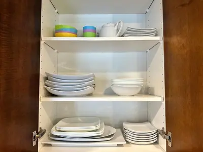 a cabinet filled with plates and bowls and dishes at S105 Canmore Stay- Hot tub, stream rm, gym, parking Mtn Retreat in Canmore