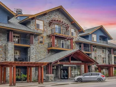 a building with a car parked in front of it at S105 Canmore Stay- Hot tub, stream rm, gym, parking Mtn Retreat in Canmore