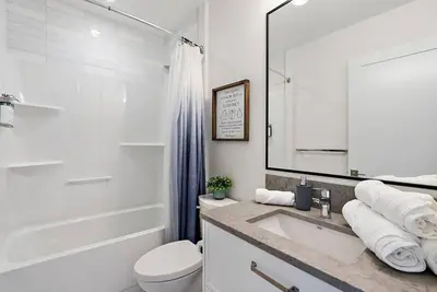 a white bathroom with a sink and a toilet at The Beach House at Saratoga Oceanfront Escape in Oyster Bay