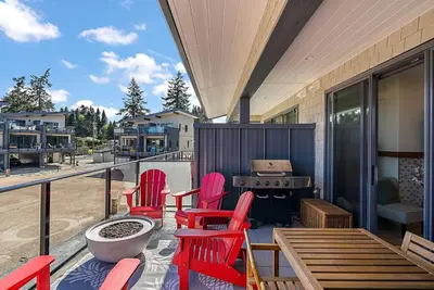a deck with red chairs and a fire pit on a house at The Beach House at Saratoga Oceanfront Escape in Oyster Bay