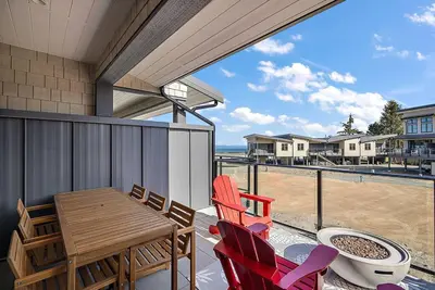 a house with a balcony with a table and chairs at The Beach House at Saratoga Oceanfront Escape in Oyster Bay
