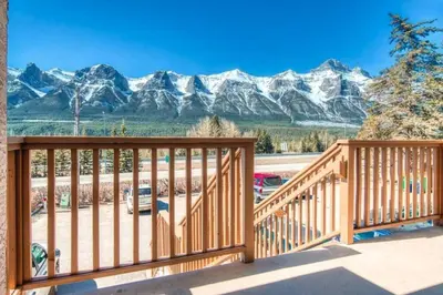 a wooden deck with mountains in the background at B212 Hot Tub, AC x3, parking, 2 min to Banff Gate in Canmore