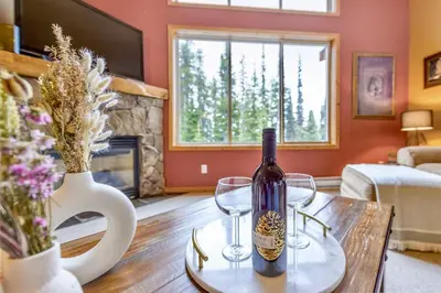 a wine bottle and two glasses on a table in a living room at Best Ski-in out 3 Bdrm Chalet, with Hot Tub in Big White