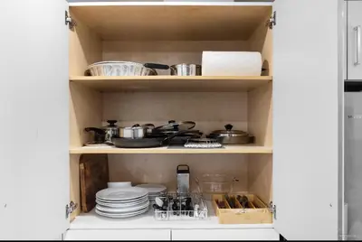 a cabinet filled with dishes and pots and pans at Entire new small home in Vancouver