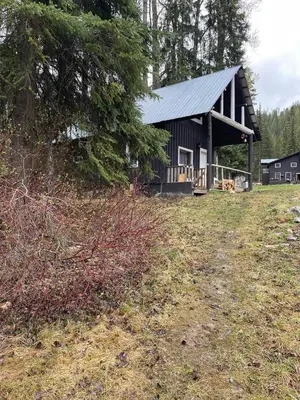 a black barn with a gambrel roof in a field at Rustic Beaverfoot Lodge Room N6 in Parson