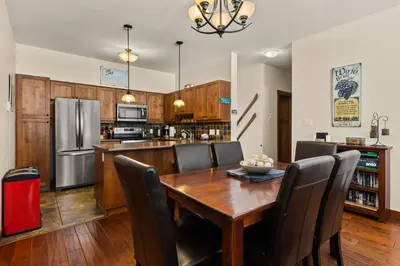 a kitchen and dining room with a wooden table and chairs at Settler's Crossing #56 ski-in ski-out condo with private hot tub in Sun Peaks