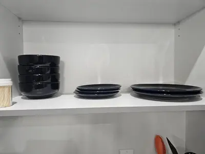 three black plates and bowls on a shelf in a kitchen at Sleek Home in Trendy Community at SW, Edmonton in Edmonton