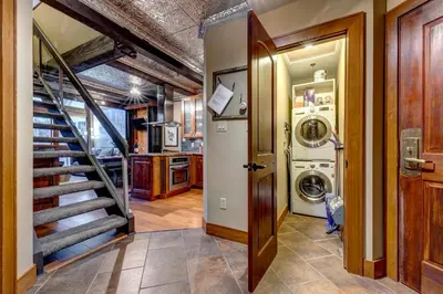 a laundry room with a staircase and a washer and dryer at Greystone Lodge 320 Ski-in Out in Whistler