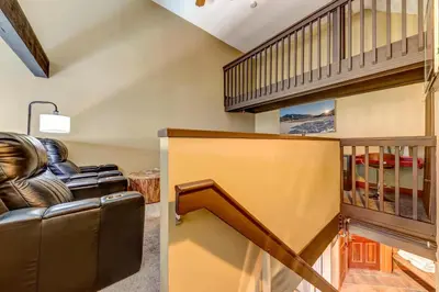 a living room with a leather couch and a stairway at Greystone Lodge 320 Ski-in Out in Whistler
