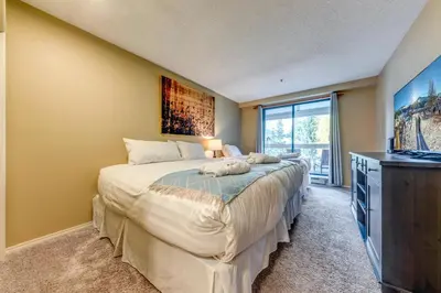 a bedroom with a large bed and a tv at Greystone Lodge 318 Ski-in Out in Whistler