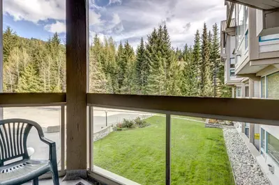 a window with a chair looking out at a yard at Greystone Lodge 332 Ski-in Out in Whistler