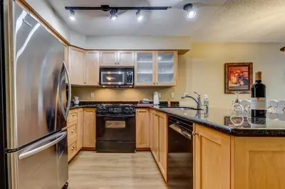 a kitchen with stainless steel appliances and wooden cabinets at Greystone Lodge 332 Ski-in Out in Whistler