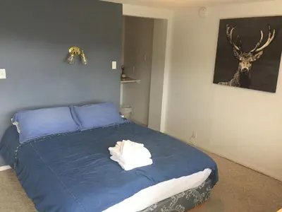 a bedroom with a bed with blue sheets and a deer picture at Cross Suite - MistyRiver Lodge in Radium Hot Springs