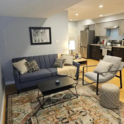 a living room with a blue couch and a kitchen at River Valley Suite Near Downtown in Edmonton