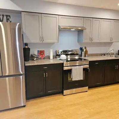 a kitchen with white cabinets and a stainless steel refrigerator at River Valley Suite Near Downtown in Edmonton
