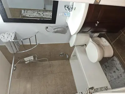 a bathroom with a toilet with a sink and a mirror at River Valley Suite Near Downtown in Edmonton