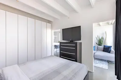 a bedroom with a bed and a flat screen tv at Cozy 1BR with AC, Chinatown, Rogers Arena, Seawall in Vancouver