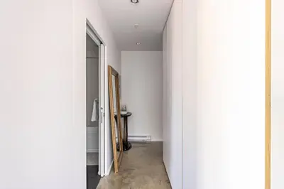a hallway with white walls and an open door at Cozy 1BR with AC, Chinatown, Rogers Arena, Seawall in Vancouver