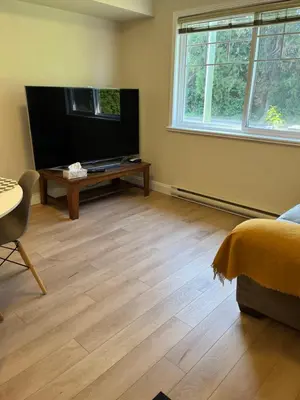 a living room with a flat screen tv and a wooden floor at 2 Beds Guest Suite to Yourself at Coquitlam Centre Mall in Port Coquitlam