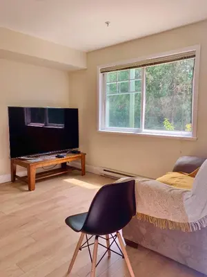 a bedroom with a bed and a tv and a chair at 2 Beds Guest Suite to Yourself at Coquitlam Centre Mall in Port Coquitlam