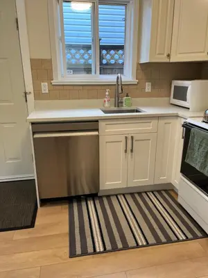 a kitchen with white cabinets and a sink and a window at 2 Beds Guest Suite to Yourself at Coquitlam Centre Mall in Port Coquitlam