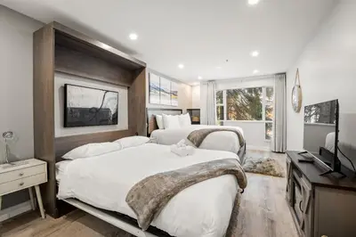 a bedroom with two beds and a television in it at Ski In & Out, Heart of Upper Village in Whistler