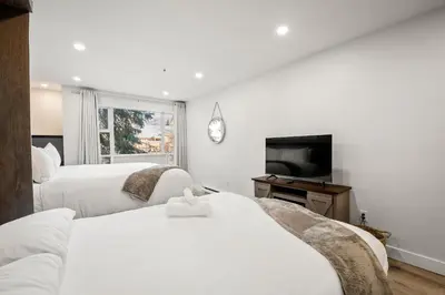 a hotel room with two beds and a television at Ski In & Out, Heart of Upper Village in Whistler