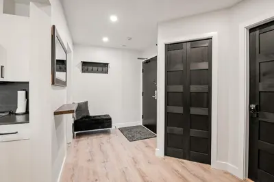 a hallway with a black door and wooden floors at Ski In & Out, Heart of Upper Village in Whistler