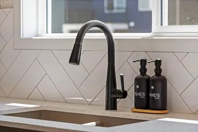 a kitchen sink with two black bottles on a counter at Entire 4 Bedroom House Including Basement with King Size Bed, Upgrade Your Stay, Netflix, Sleeps 14 in Balzac