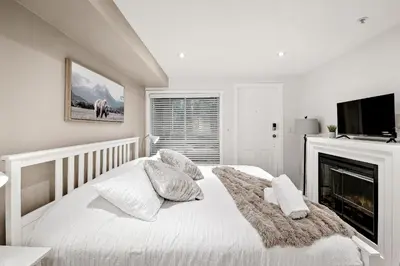a white bedroom with a bed and a fireplace at Whistler Village, Private Hot Tub, Free Parking in Whistler