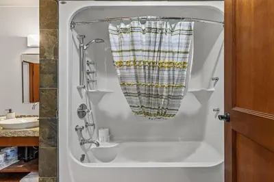 a bath tub in a bathroom with a shower at L109 Canmore World Class Solara Resort - Hot tub, Pool, Gym, AirCon, Free Parking & Netflix in Canmore
