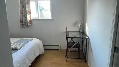 a bedroom with a bed and a desk and a window at Big band home in Burnaby