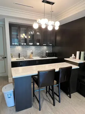 a kitchen with a large island with black cabinets and chairs at Private Rooms in Vancouver West in Vancouver
