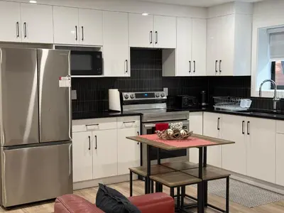 a kitchen with white cabinets and a stainless steel refrigerator at Calm & Cozy Private Suite in Surrey