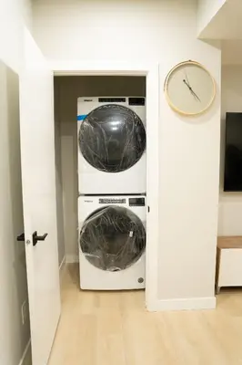 a washer and dryer in a room with a clock at The Old Trafford - Stylish 2 bed suite in Calgary