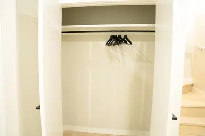a closet with white walls and black hangers at The Old Trafford - Stylish 2 bed suite in Calgary