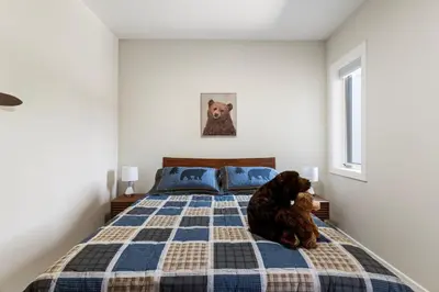 a teddy bear sitting on a bed in a bedroom at Luxe Retreat by Canadian Rockies Vacation Rentals in Canmore