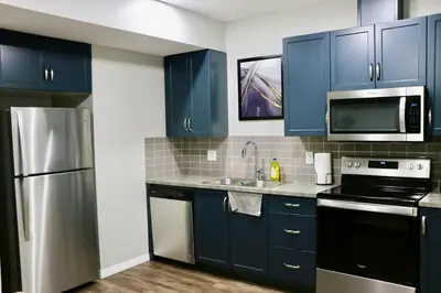 a kitchen with blue cabinets and a stainless steel refrigerator at Parkside Luxury Stay with Xbox Entertainment in Calgary