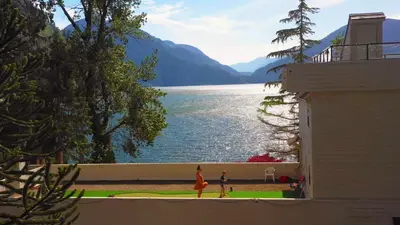 two people walking on a balcony with a view of a lake at Ozarks Luxurious Lakeside Villa at Harrison Lake in Harrison Hot Springs