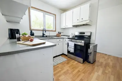 a kitchen with white cabinets and a stove top oven at Cozy House in Haines Junction in Haines Junction