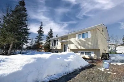 a house with a pile of snow in front of it at Cozy House in Haines Junction in Haines Junction