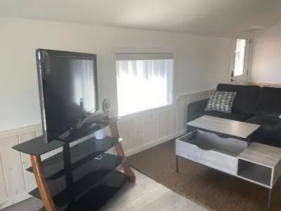 a living room with a black couch and a flat screen tv at Lakeside Cottage in Nanaimo