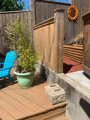 a wooden deck with a blue chair and a sunflower at Best Bed and Breakfast in Port Alberni